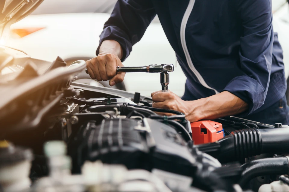 Un mécanicien automobile travaille sous le capot d'un véhicule dans un garage