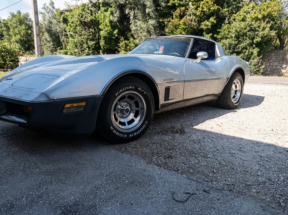 Chevrolet Corvette C3 silver métallique, stationnée sur gravier, vue trois-quarts avant gauche