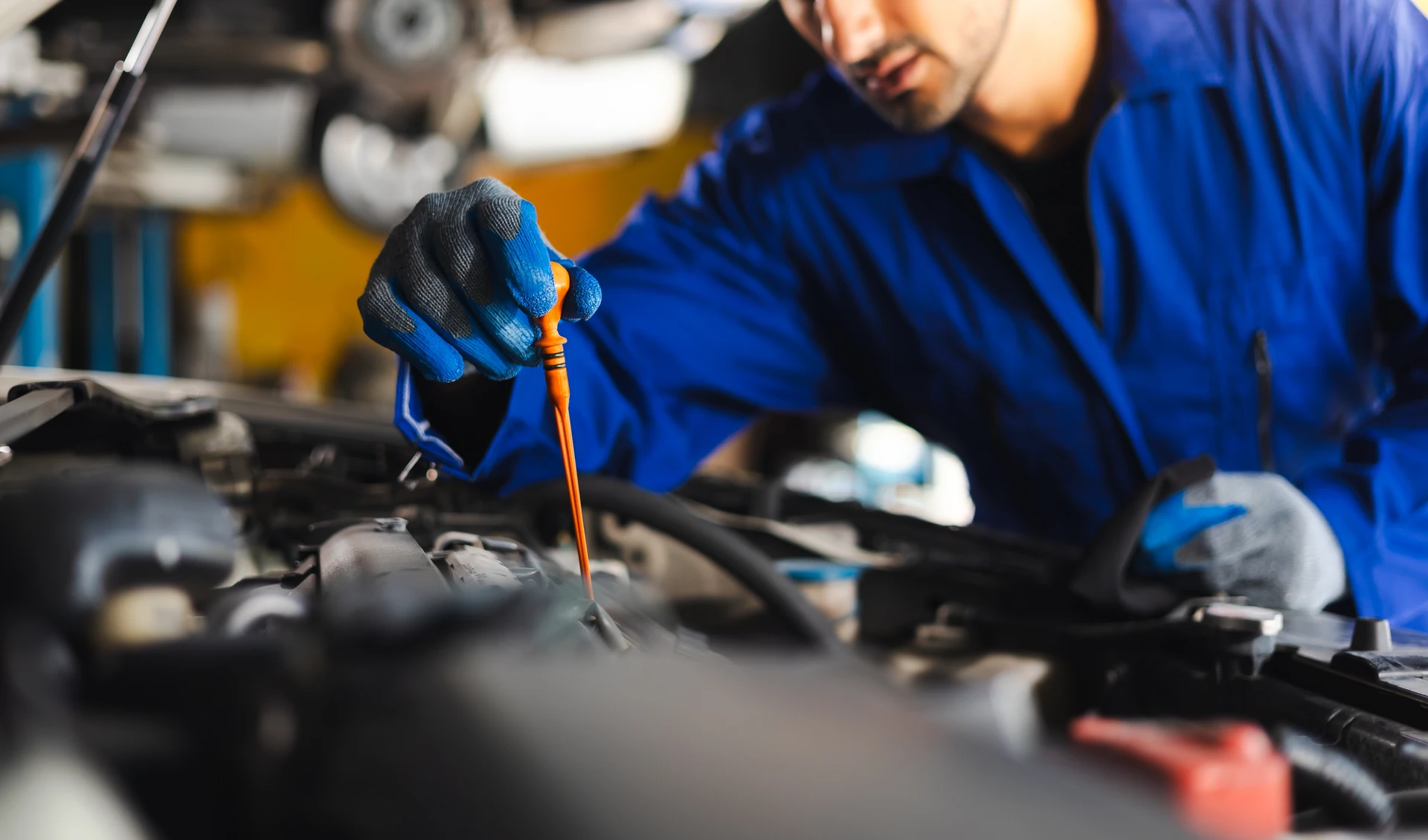Mécanicien automobile dans atelier professionnel effectuant diagnostic électronique sur véhicule, capot ouvert, connecté à station de diagnostic verte